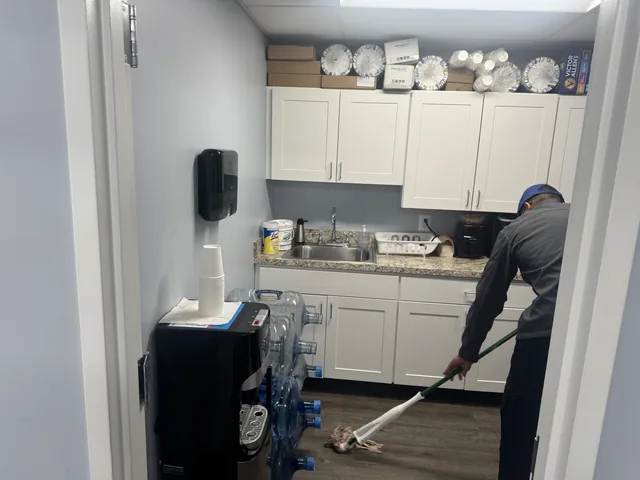 A Higeniks cleaner mopping the floor of an office break room.