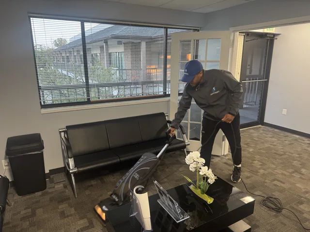 A Higeniks cleaner vacuuming the carpet of an office lounge after hours.