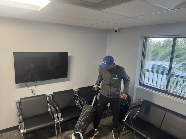 A Higeniks cleaner vacuuming a waiting room between rows of chairs.
