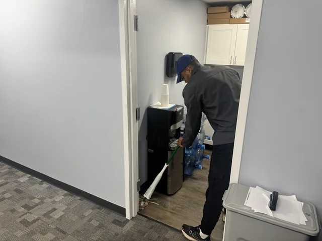 A Higeniks cleaner mopping the floor beside an office water cooler.